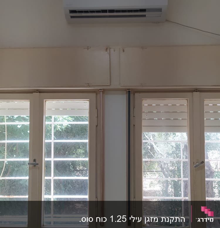 מזגן מותקן על קיר מעל חלונות עם תריסים